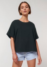 Zwarte T-shirt met korte mouwen in een losse pasvorm, gemaakt van zachte katoen, met een ronde halslijn en opgerolde mouwen, gecombineerd met lichte denim shorts.