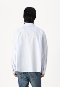 Long-sleeve, button-up shirt in light blue with thin white stripes; features a classic collar and relaxed fit. Suitable for casual wear.
