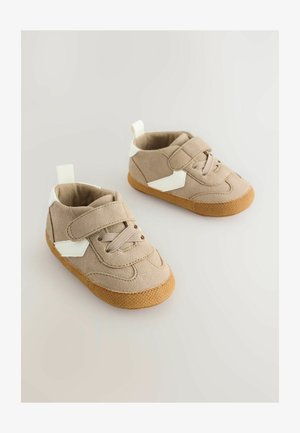 Beige Wildleder-Sneakers für Kleinkinder mit weißen Akzenten und Klettverschluss, ausgestattet mit einer strukturierten Gummisohle und einem stützenden Knöcheldesign.
