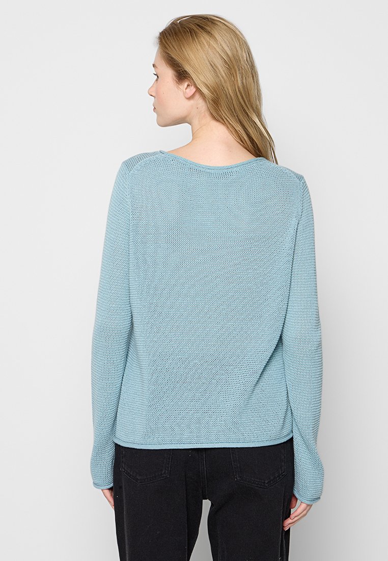 Helles blaues Strickpullover mit strukturiertem Finish, rundem Ausschnitt und langen Ärmeln, der eine lockere Passform und ein einfaches Design zeigt.