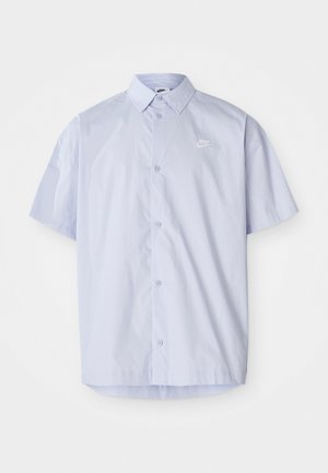 Light blue short-sleeve shirt made of smooth fabric, featuring a button-down design and a small white Nike logo on the chest.