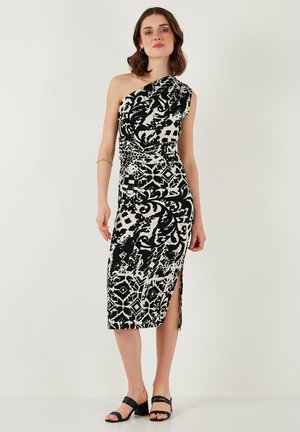 Black and white one-shoulder dress with a fitted design, features abstract patterns, side slit, and ruched waist, made of smooth fabric.