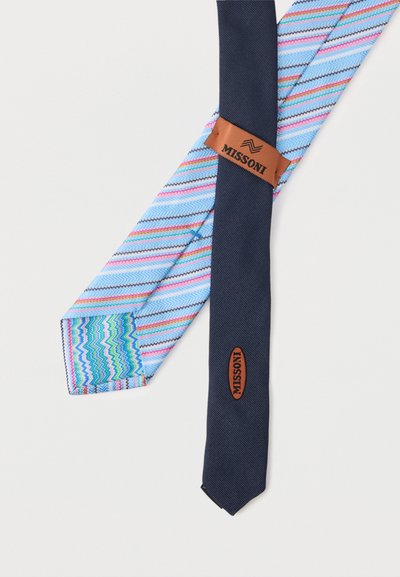 Cravate en soie bleu clair avec des rayures en zigzag multicolores et un dos uni bleu marine, arborant des étiquettes de marque Missoni marron de chaque côté.