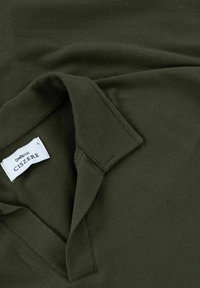 Olivgrünes Polohemd aus strukturiertem Stoff. Mit umgeschlagenem Kragen, Etikett mit "CISZERE" und einem schlichten, eleganten Design.