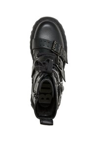 Botines negros con un acabado en cuero texturizado, correas ajustables con hebilla y una suela de goma resistente con un diseño de relieve contrastante.