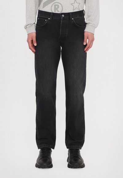 Schwarze Jeans aus Denim mit geradem Schnitt, Fünf-Taschen-Design und silbernen Beschlägen. Im Outfit kombiniert mit einem hellgrauen Langarmshirt und schwarzem Schuhwerk.