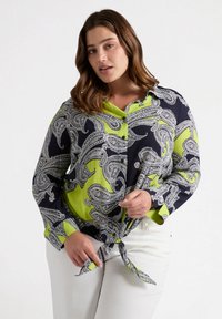 Camisa de manga larga con un patrón de cachemira en azul marino y verde lima, con botones en la parte delantera y detalle de dobladillo anudado. Fabricada con un tejido ligero.