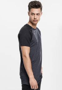 Short-sleeve t-shirt with a black rounded collar, gray body, and black sleeves. Soft fabric with a slightly fitted design and straight hem.