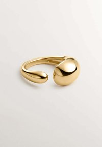 Pulsera de metal en tono dorado con un diseño suave y redondeado que presenta dos extremos abultados; acabado brillante y curvatura sin costuras.