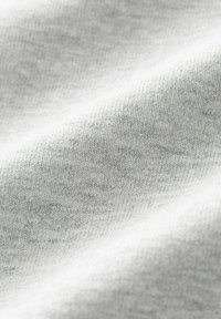 Šedá pletená tkanina s hladkým, textúrovaným povrchom, ktorá obsahuje jemné, variabilné pramene a subtílne heathered detaily v ľahkom zložení.