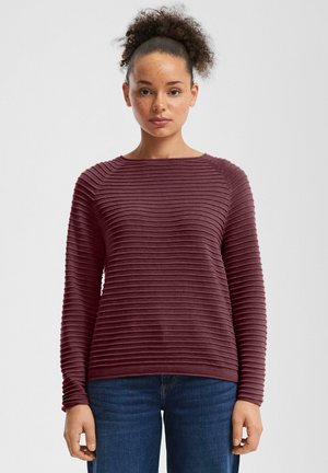 Pull en vin à manches longues avec une texture à côtes horizontales, un col rond et une coupe décontractée. Associé à un jean en denim bleu.