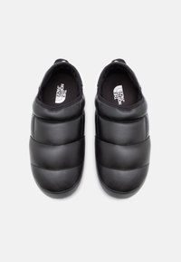 Fekete slip-on cipők párnázott kialakítással. Simább anyagból készültek, logóval és vízszintes varrási díszítéssel.