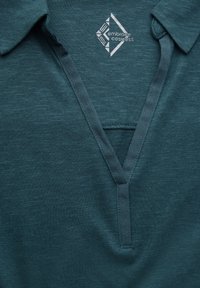 Türkisfarbenes Polohemd aus strukturiertem Stoff mit V-Ausschnitt und geripptem Kragen. Mit einem weißen Logo auf der Brust.