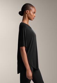 Mustat, rento t-paita, jossa on lyhyet hihat ja pyöreä pääntie, valmistettu pehmeästä materiaalista; kapeneva helma ja rento siluetti.