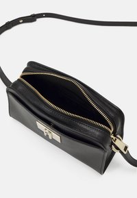 Borsa a tracolla in pelle nera con zip dorata, doppie comparti e chiusura in metallo. Texture liscia con finitura ruvida. Cinghia regolabile.