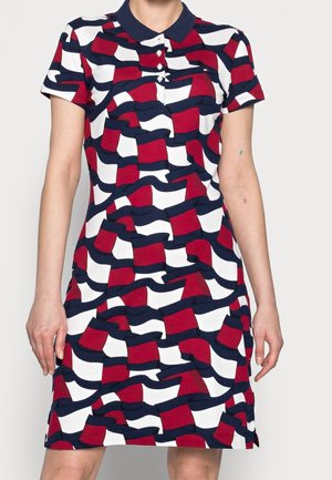 Sukienka polo z krótkim rękawem, z granatowym kołnierzem oraz wyrazistym, falistym wzorem w kratę w kolorach czerwonym, białym i granatowym, o dopasowanym kroju.