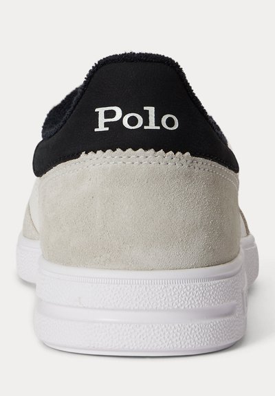 Πίσω όψη ενός μπεζ σουέτ αθλητικού παπουτσιού με λευκή σόλα και μαύρο κολάρο, με λευκή ένδειξη "Polo" στη φτέρνα.