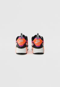 Nike Air lenkkarit mustalla päällisellä, neonpinkin ja oranssin yksityiskohdin sekä valkoisella pohjalla. Varustettu vetolenkillä ja tekstuurilla varustetulla kantapäällä.