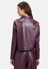 Fioletowa skórzana kurtka typu cropped z wyciętym kołnierzem, gładką teksturą i prostymi liniami. Posiada tylną yoke i dopasowane rękawy.