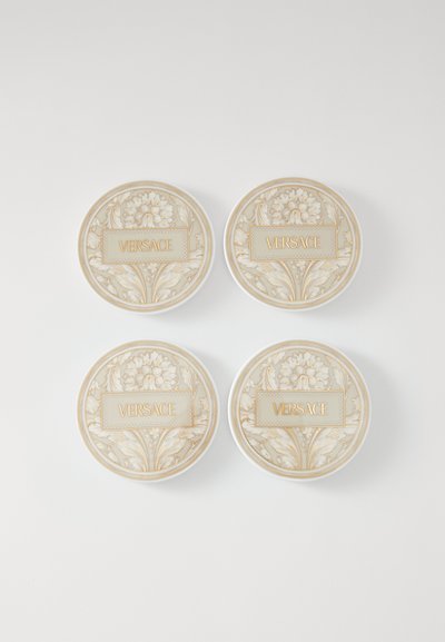 Sada čtyř kulatých podtácků s béžovým květinovým vzorem a zlatými akcenty, uprostřed s vyraženým slovem "VERSACE".