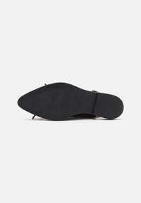 Black rubber sole of a shoe featuring a smooth texture and subtle ridges. Design includes a slender shape with a slight heel.