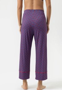 Paarse pyjamabroek met rood bloemenpatroon, wijduitlopende ontwerp, zachte stof en contrasterende rode bies bij de boorden. Middenhoge tailleband.