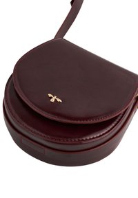 Compact dark burgundy leather crossbody bag with rounded flap and small gold bee emblem on front, featuring matching stitching and strap.
