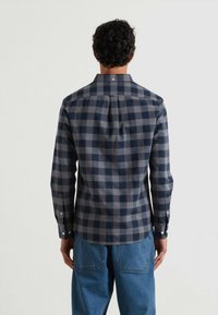 Chemise �à manches longues à carreaux bleus et gris avec un col boutonné et des boutons aux poignets, fabriquée en coton, dotée d'un ourlet arrondi et d'un détail au niveau du dos.