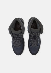 Σκούρες μπλε ορειβατικές μπότες με σκληρό σχέδιο, υφασμάτινη επένδυση με υφή, μοτίβο κορδόνια και ενισχυμένες μύτες και φτέρνες.