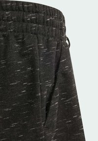 Pantalones deportivos negros con una tela texturizada y manchas blancas, cinturilla elástica y un bolsillo lateral.