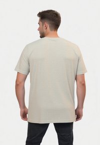 Lys grå kortærmet T-shirt lavet af tekstureret materiale, med en afslappet pasform og subtile syninger ved kanten.