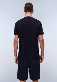 Mørkeblå bomulds T-shirt med korte ærmer, rund halsudskæring og lige bund, parret med mørke shorts. Ingen synlige logoer eller mønstre.