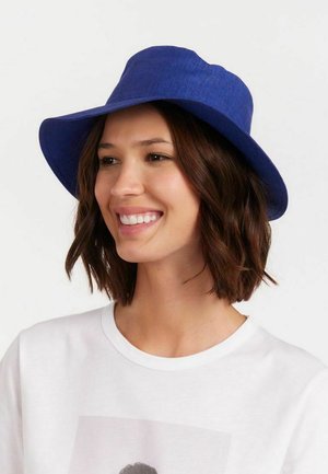 Chapeau fedora bleu en tissu texturé avec une large visière, arborant un design structuré et une légère courbure ascendante sur les bords.