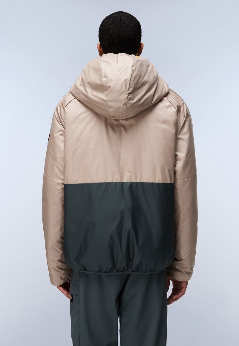 Chaqueta acolchada con una sección superior beige y una sección inferior verde oscuro. Presenta una capucha y un dobladillo elástico para un ajuste ceñido.