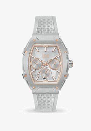 Srebrn oktagonalni ur s teksturiranim belim silikonskim trakom. Ima naglaske u rosegold boji, više poddijalova i sjajnu srebrno lice.