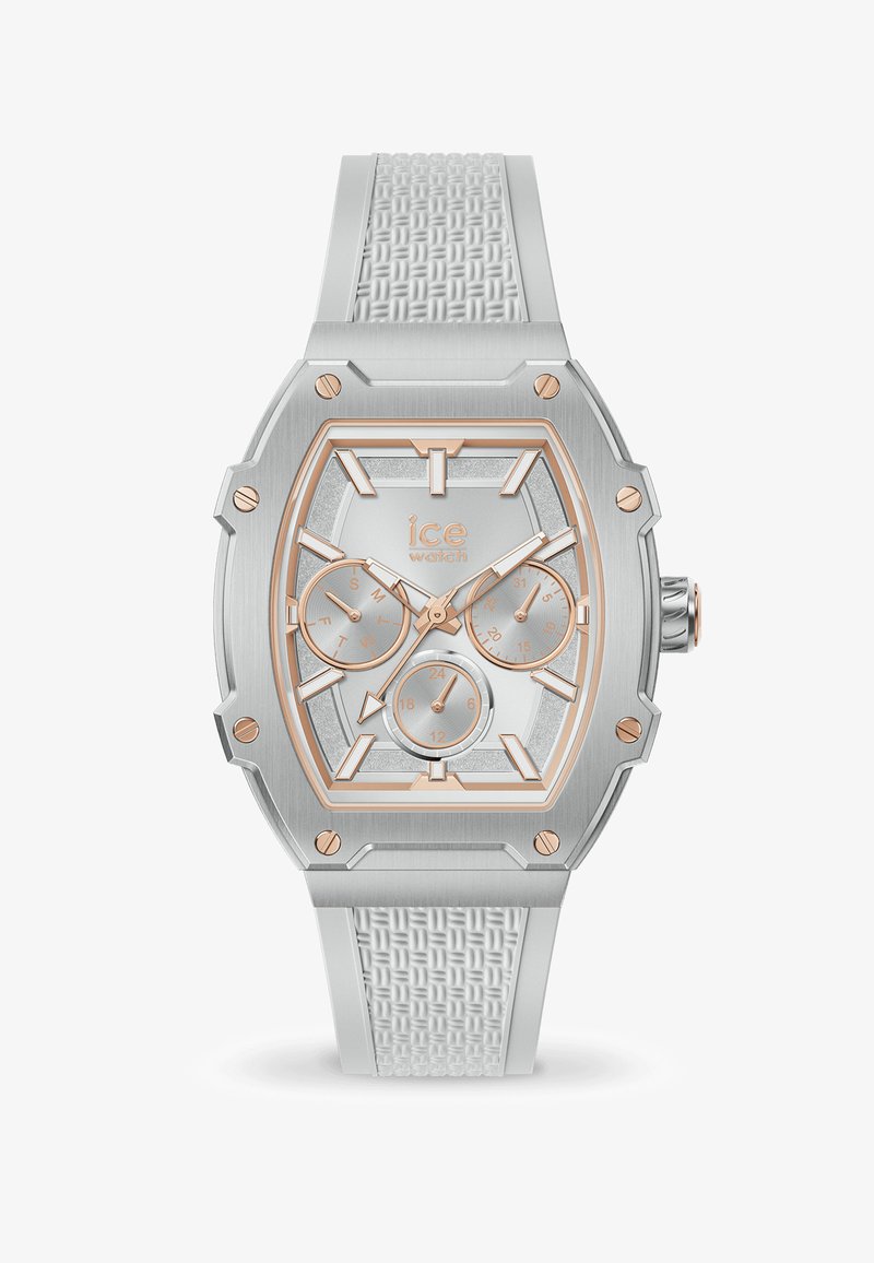 Sudraba tonēta astoņstūra pulkstenis ar teksturētu balto silikona siksniņu. Iezīmēts ar rožu zelta akcentiem, vairākiem subpulksteņiem un mirdzošu sudrabainu seju.