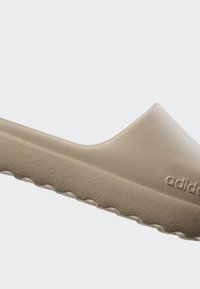 Beige halksandaler med en slät, matt yta, rundade kanter och texturerad sula med zick-zack mönster; märkt "adidas" på sidan.