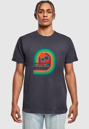 Dark grey t-shirt featuring a colorful retro graphic of palm trees and text. The design includes red, yellow, green, and blue stripes.