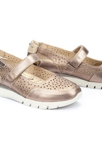 Chaussures slip-on en or rose métallique avec un design perforé, une sangle ajustable, un bout rond et une semelle en caoutchouc blanche. Légères et respirantes.