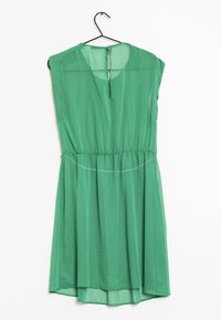 Vestido verde, ligero, con mangas cortas, cintura fruncida y detalle de ojal en la espalda. Tejido texturizado con pequeños patrones de puntos.