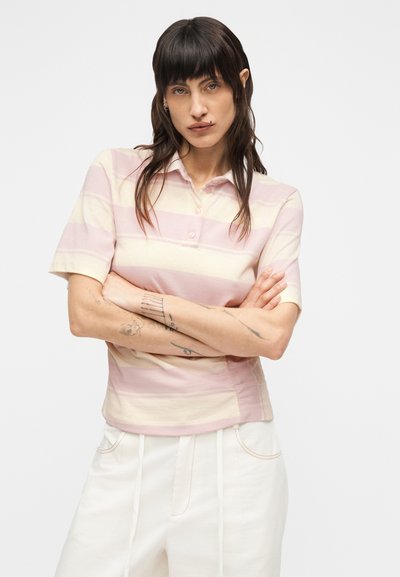 Μπλούζα πόλο σε απαλό ροζ με οριζόντιες κρεμ ρίγες, κοντά μανίκια, κουμπωτή πλακέτα και εφαρμοστή σχεδίαση. Ελαφρύ ύφασμα.