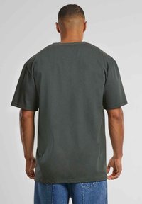 Dark green cotton t-shirt with short sleeves, a round neck, and a relaxed fit. The fabric has a smooth texture and no visible patterns or graphics.