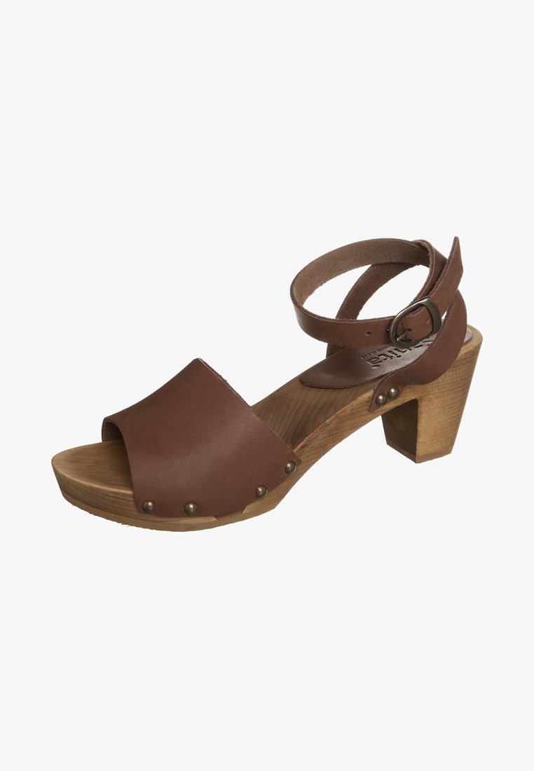 Sandale en cuir marron à bout ouvert, talon bloc en bois, bride de cheville avec boucle et clous en métal le long du bord de la semelle.