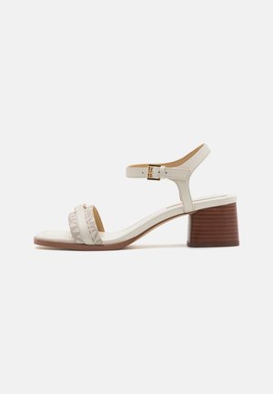 Sandalia de tacón blanco con dos tiras y acentos texturizados, con un tacón cuadrado y una correa ajustable en el tobillo con una hebilla dorada.