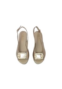 Sandali beige con zeppa, open toe, con una fibbia lucida come accento, texture liscia e un tacco leggero. La soletta presenta la scritta del marchio.