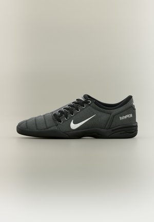 Μαύρο ποδοσφαιρικό παπούτσι Nike Total90 III με χαμηλό προφίλ, λευκό λογότυπο Swoosh και κορδόνια σε ουδέτερο φόντο.