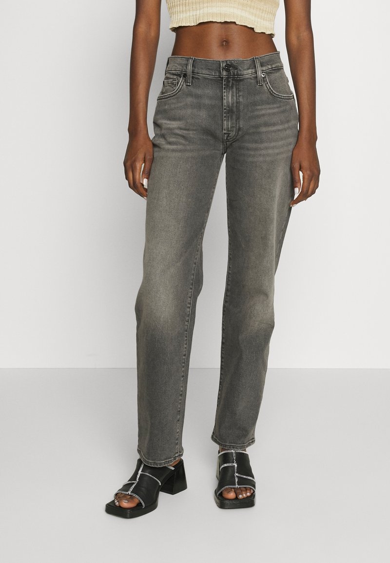 Jeans grigi alti in vita, a gamba dritta, con dettagli strappati e tasche anteriori, abbinati a sandali neri con tacco a blocco.