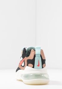 Tenisky Nike s černým, hnědým a světle modrým designem, s výrazným červeným swooshem, průhlednou podrážkou a polstrovaným patním poutkem.