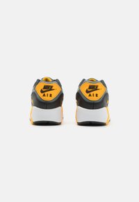 Nike jooksujalatsid mustades ja hallides toonides, erksate kollaste aktsentidega. Paks valge tald, tekstuuriga tagakreen logo detailidega, pehmendatud kael.