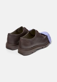 Brown leather shoes with a purple rubber overlay, viewed from the back. The shoe features a sturdy sole and a smooth finish.
